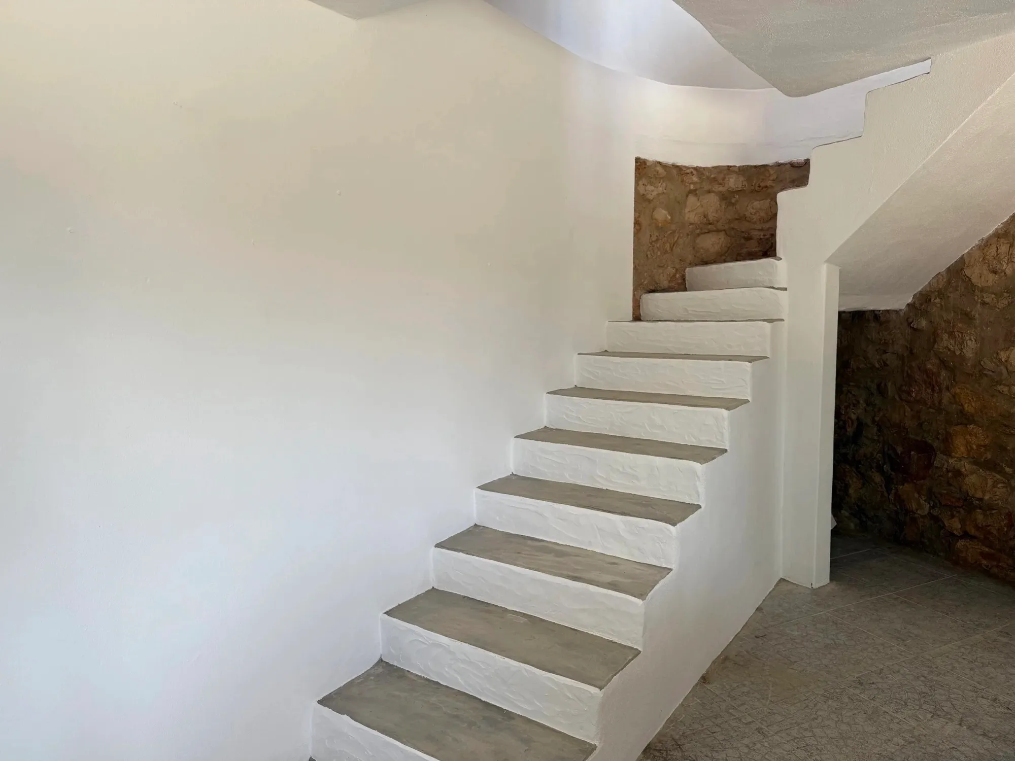 Escada interior revestida, com parede de pedra à vista